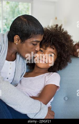 Großmutter küsst Enkelin im Wohnzimmer Stockfoto