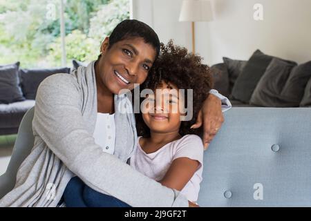 Glückliche Großmutter und Enkelin sitzen auf dem Sofa Stockfoto