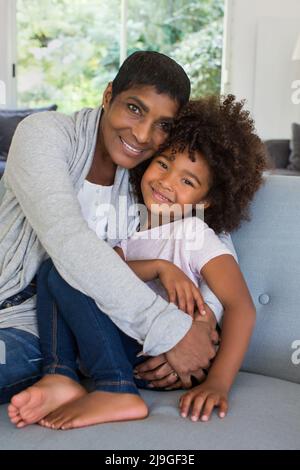 Großmutter und Enkelin sitzen auf einem Sofa im Wohnzimmer Stockfoto