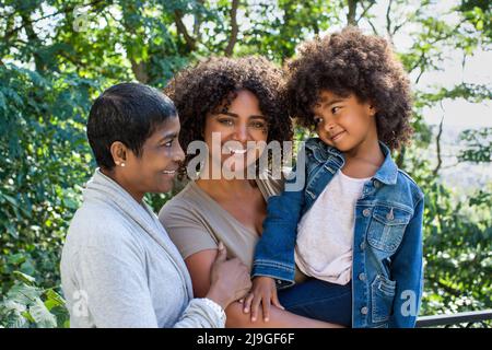 Lächelnde Mutter schaute auf die Kamera, während Enkelin und Großmutter einander anschauend waren Stockfoto