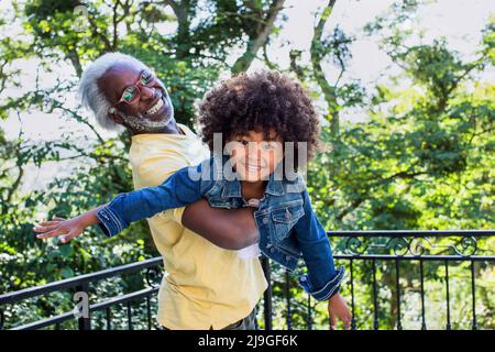 Enkelin spielt mit ihrem Großvater auf dem Balkon Stockfoto