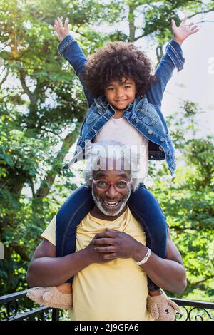 Enkelin spielt mit ihrem Großvater auf dem Balkon Stockfoto