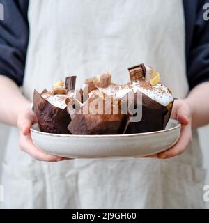 Frau hält glasierte Osterkuchen mit Schokolade und Süßigkeiten, Hausküche Hintergrund dekoriert Stockfoto