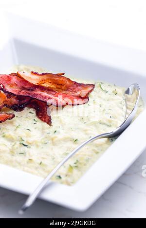 Zucchini-Suppe mit Speckstreifen Stockfoto