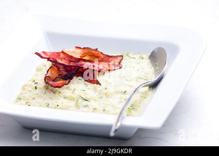 Zucchini-Suppe mit Speckstreifen Stockfoto