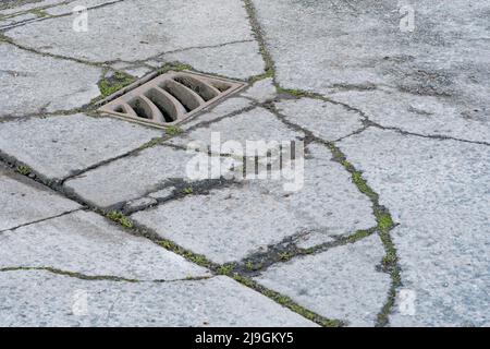 Schlüsselabfluss auf einem Abschnitt eines Industriehofes. Metapher für „Drain“ oder das Abwerfen von etwas gleichem. Konzeptbrüche. Der Schwerpunkt liegt auf Metallgitters. Stockfoto