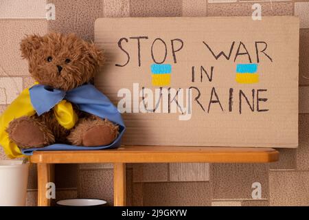 Stoppen Sie den Krieg in der Ukraine je geschrieben auf einem Schild, das auf Regal in der Ukraine in der Nähe eines Teddybären steht. Frieden in der Ukraine. Protest Stockfoto