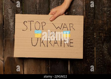 Stoppen Sie den Krieg in der Ukraine geschrieben auf einem Zeichen, dass eine Frau in ihren Händen hält von ihrem Haus in der Dnjepr, Protestaktion, Kriegsrecht in der Ukraine Stockfoto
