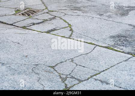 Schlüsselabfluss auf einem Abschnitt eines Industriehofes. Metapher für „Drain“ oder das Abwerfen von etwas gleichem. Konzeptbrüche. Der Schwerpunkt liegt auf Metallgitters. Stockfoto