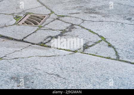 Schlüsselabfluss auf einem Abschnitt eines Industriehofes. Metapher für „Drain“ oder das Abwerfen von etwas gleichem. Konzeptbrüche. Der Schwerpunkt liegt auf Metallgitters. Stockfoto