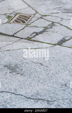 Schlüsselabfluss auf einem Abschnitt eines Industriehofes. Metapher für „Drain“ oder das Abwerfen von etwas gleichem. Konzeptbrüche. Der Schwerpunkt liegt auf Metallgitters. Stockfoto