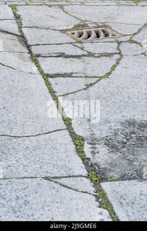 Schlüsselabfluss auf einem Abschnitt eines Industriehofes. Metapher für „Drain“ oder das Abwerfen von etwas gleichem. Konzeptbrüche. Der Schwerpunkt liegt auf Metallgitters. Stockfoto