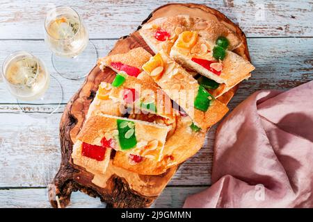 Coca de Sant Joan auf Holzbrett mit Gläsern Champagner auf dem Tisch. Traditionelles süßes Baumkett in Katalonien für Sant Joan Nachtfeier, Draufsicht Stockfoto