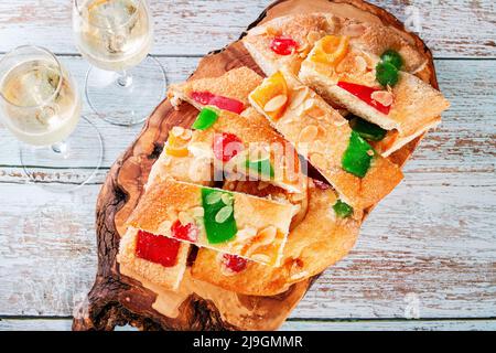 Coca de Sant Joan auf Holzbrett mit Gläsern Champagner auf dem Tisch. Traditionelles süßes Baumkett in Katalonien für Sant Joan Nachtfeier, Draufsicht Stockfoto