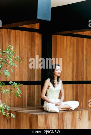 Frau meditiert im Six Senses Spa, Heritance Kandalama Hotel, Dambulla, Sri Lanka. Eine Frau sitzt im Lotusstil und meditiert mit geschlossenen Augen. Stockfoto