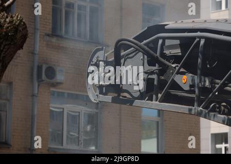 Das Straßenfräsfahrzeug lädt gefrästen Asphalt in einen Muldenkipper in einem engen Innenhof mit alten Häusern. Stockfoto