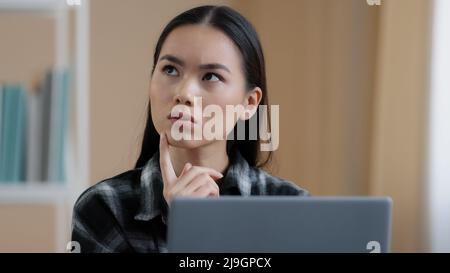 Denken Student Mädchen asiatisch nachdenklich Frau Porträt arbeitet Laptop tun Online-Aufgabe auf der Suche nach Problemlösung fühlt sich zweifelhaft tief in Gedanken macht Stockfoto