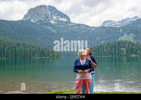 Zwei Frauen sind, die auf dem Hintergrund der Glazial- Schwarzer See im Durmitor nationale UNESCO Park in der Nähe der Stadt Zabljak, Montenegro. Stockfoto