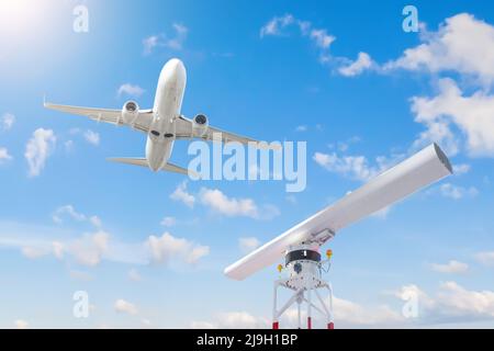 Drehlokalisator auf dem Gebiet des Flughafens und ein Passagierflugzeug, das in den Himmel abfliegt Stockfoto