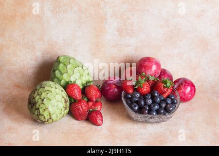 Obstgruppe auf abstraktem Studiohintergrund bestehend aus Pudding-Äpfeln, Erdbeeren, Blaubeeren und Pflaumen. Gesunde Ernährung. Stockfoto