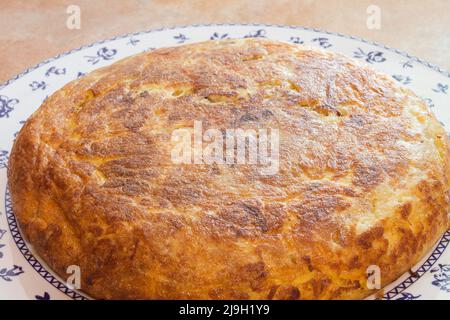 Nahaufnahme eines großen Kartoffelomeletts auf einem dekorativen Teller. Hausgemachte und traditionelle Speisen. Stockfoto