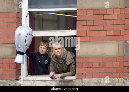 Manchester City-Fans blicken während der Premier League-Trophäenparade in Manchester aus einem Fenster. Bilddatum: Montag, 23. Mai 2022. Stockfoto