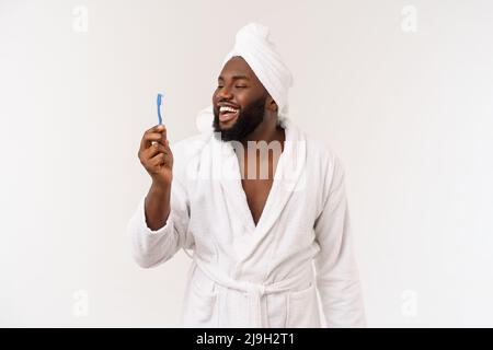 Porträt eines glücklichen jungen dunklen anm, der seine Zähne mit schwarzer Zahnpasta auf weißem Hintergrund putzt. Stockfoto