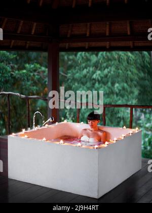 Frau in einem Milchbad bei Kerzenschein, Kayumanis Spa, Kayumanis Ubud, Bali, Indonesien. Stockfoto