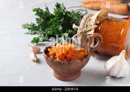 Hausgemachter Gemüsekaviar aus Karotten, Paprika, Knoblauch und Tomaten in einer Schüssel und einem Glas auf hellem Hintergrund Stockfoto