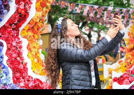 Chelsea, London, Großbritannien. 23.. Mai 2022. Paulina, die in Bloom mit Chelsea zusammenarbeitet, posiert mit der Installation. Der grazende Sloane Square ist ein 1oft m hoher Queen's Head in einem Blumenteppich, Teil von Chelsea im Bloom's 'British Icons'-Thema und das Jubiläum in diesem Jahr. Chelsea in Bloom ist ein lustiger jährlicher Wettbewerb zwischen vielen Unternehmen, Geschäften und Restaurants in Chelsesa mit aufwendigen öffentlichen Blumenausstellungen und läuft parallel zur Chelsea Flower Show. Kredit: Imageplotter/Alamy Live Nachrichten Stockfoto