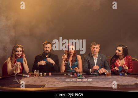 Eine Gruppe junger wohlhabender Freunde spielt Poker in einem Casino. Stockfoto