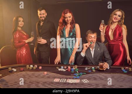 Eine Gruppe junger wohlhabender Freunde spielt Poker in einem Casino. Stockfoto