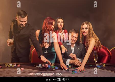 Eine Gruppe junger wohlhabender Freunde spielt Poker in einem Casino. Stockfoto