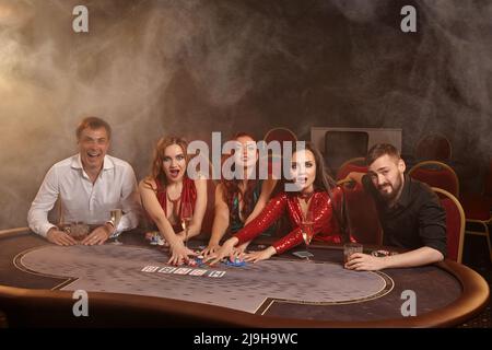 Eine Gruppe junger wohlhabender Freunde spielt Poker in einem Casino. Stockfoto