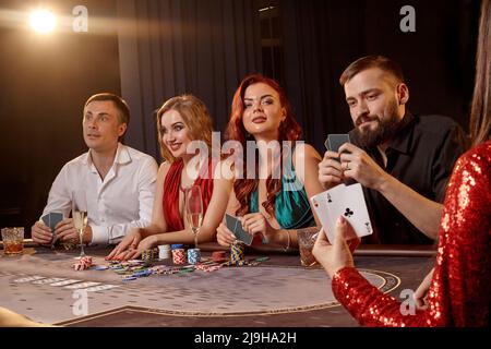 Eine Gruppe junger wohlhabender Freunde spielt Poker in einem Casino. Stockfoto