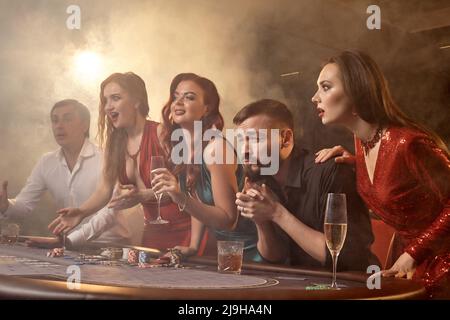 Eine Gruppe junger wohlhabender Freunde spielt Poker in einem Casino. Stockfoto