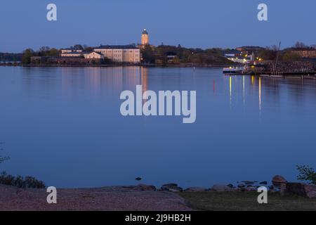 Helsinki / Finnland - 22. MAI 2022: Suomenlinna Festung auf der anderen Seite des Flusses. Ein Leuchtturm, der Spiegelungen auf das ruhige Meer wirft. Stockfoto