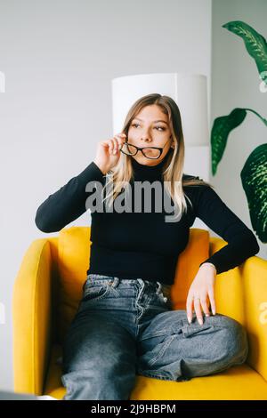 Junge kaukasische Frau, die in einem Optikerladen eine Brille anprobiert. Stockfoto