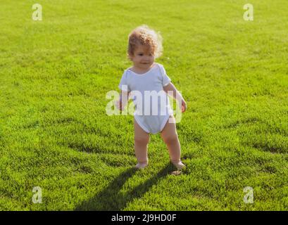 Baby Junge Kleinkind zu Fuß in einem Park am hellen Frühlingstag. Entwicklung von Kindern. Stockfoto