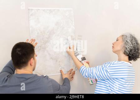 Frau und Freundin mit Tapeten und Farbmustern an der Wand Stockfoto