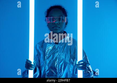 Frau mit beleuchteten Neonlichtern vor blauem Hintergrund Stockfoto