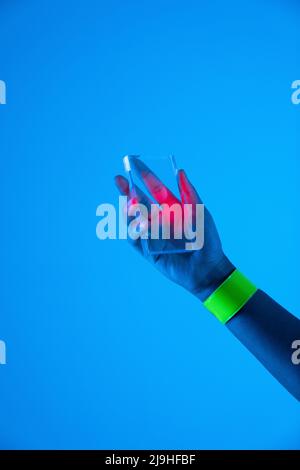 Hand der Frau mit futuristischem transparentem Smartphone vor blauem Hintergrund Stockfoto