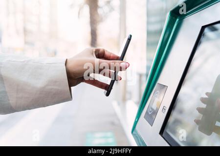 Frau, die kontaktlos über das Smartphone bezahlt Stockfoto