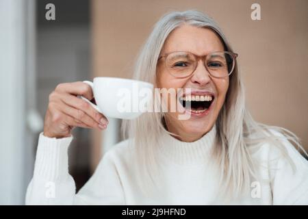 Fröhliche ältere Frau mit Kaffeetasse Stockfoto