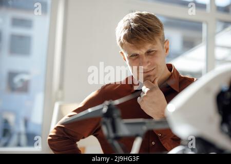 Nachdenklicher Geschäftsmann untersucht Drohne im Büro Stockfoto