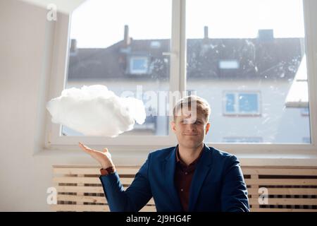 Lächelnder Geschäftsmann mit schwebendem Cloud-Netzwerk im Büro Stockfoto
