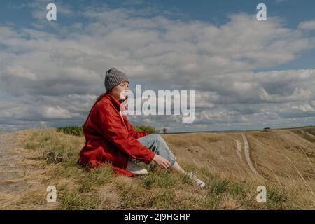 Junge Frau, die am Wochenende auf dem Feld sitzt Stockfoto