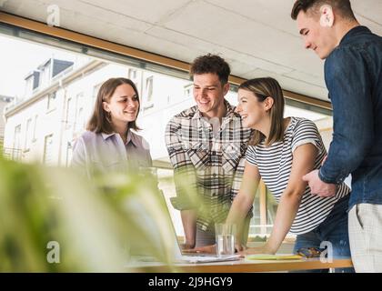 Lächelnde junge Geschäftsleute, die sich im Büro treffen Stockfoto