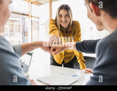 Glückliches Geschäftsteam, das die Fäuste im Büro anfasst Stockfoto