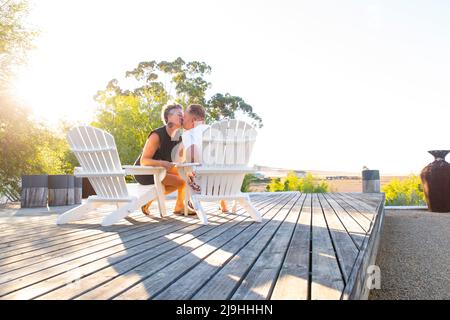 Das Paar küsst sich gegenseitig, sitzt auf dem Stuhl auf der Terrasse Stockfoto